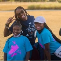 A Girls on the Run coach smiles with two GOTR girls 